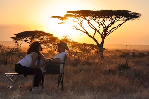 Luxury African Safari for wedding couple. Bridal couple sitting with sunset